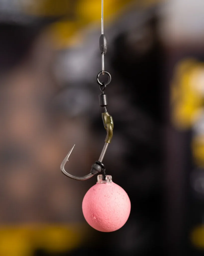 Close-up of a Ronnie (spinner) rig with a curved hook, swivel and a pink pop-up hookbait hanging.